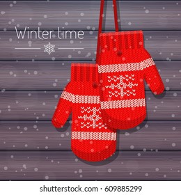 Vector illustration of winter knitted mittens for girls. Realistic wooden background with snowflakes. Winter holidays card in flat style.