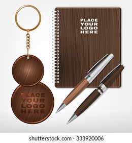 Vector illustration of a wooden and metal souvenirs with a rings for a key, notebook and pens Isolated on a white background. Ideal template for branding, identity guidelines and promo campaigns.