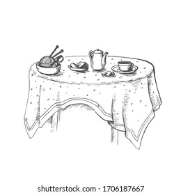 Vector image of a table with a tablecloth and teapots standing on it, a cup, a ball and knitting needles and candy