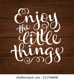 Vector inscription with ornamental elements on wood background. "Enjoy the little things" poster or postcard. Typography collection