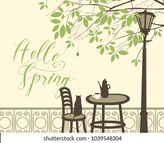 Vector landscape with a handwritten lettering Hello Spring. Street cafe with tea or coffee on the table, cat on the chair under the branches of a tree with green leaves and the spider in the cobweb