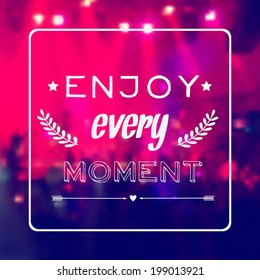 Vector motivational card "Enjoy every moment". Blurred background with rock stage and crowd. 