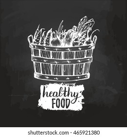 Vector organic vegetables logo. Farm eco products illustration. Hand sketched wooden basket with greens on chalkboard.