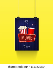 Vector poster hanging on paper clips with pop corn basket, cola cup and movie sign on blue curtain background. It's movie time banner template.