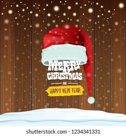 vector red Santa hat with greeting text Merry Christmas and happy new year on wooden background with falling snowflakes. Funny Merry christmas greeting card, banner or poster xmas background.