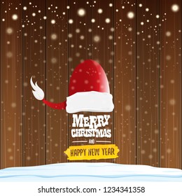 vector red Santa hat with greeting text Merry Christmas and happy new year on wooden background with falling snowflakes. Funny Merry christmas greeting card, banner or poster xmas background.