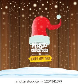 vector red Santa hat with greeting text Merry Christmas and happy new year on wooden background with falling snowflakes. Funny Merry christmas greeting card, banner or poster xmas background.