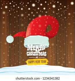 vector red Santa hat with greeting text Merry Christmas and happy new year on wooden background with falling snowflakes. Funny Merry christmas greeting card, banner or poster xmas background.