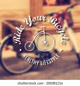 Vector Retro typography. Hipster Label in defocused background with bike at a city downtown. Quote "Ride your bicycle. Healthy Lifestyle".