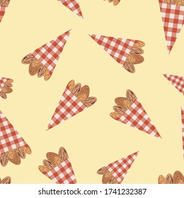 Vector roasted almond nuts in cute red gingham paper bags seamless pattern background. Brown oval seeds on yellow backdrop. Kernel shells repeat for food fair, confectionery, farmers market concept