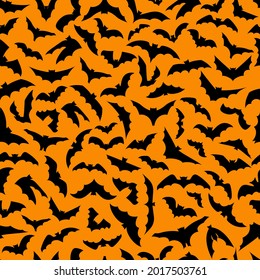 Vector seamless background for Halloween design. 
Seamless pattern with black flying bats isolated on orange background. Scary Halloween traditional design element. 