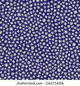 Vector seamless floral pattern from small white daisy and chamomile
flowers in chaotic order. Trendy millefleurs style, dark blue background. Batik, wallpaper, wrapping paper, chintz textile print