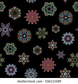 Vector seamless pattern with abstract hand drawn blue, orange and neutral snowflakes design on a black background. Hand painted pattern.