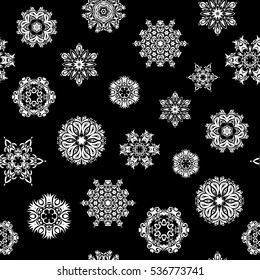 Vector seamless pattern with abstract hand drawn white snowflakes design on a black background. Hand painted pattern.