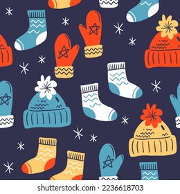 Vector seamless pattern on dark background. Mittens and warm socks and hats for winter holidays. Cozy winter texture for gifts, wrapping paper and others.