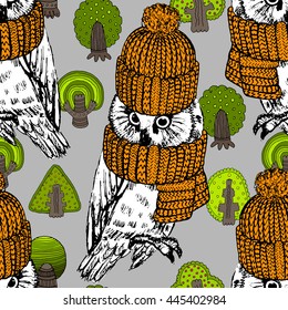 Vector seamless pattern with owls and trees. White owl in a orange knitted hat and scarf.