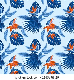 Vector  seamless pattern of tropical blue palm leaves, monstera  leaves  and coral flowers of the bird of paradise (Strelitzia) plumeria on a light blue background. Wallpaper trend design.