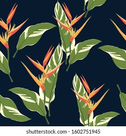 Vector seamless tropical pattern, vivid tropic foliage, with palm leaves, bird of paradise flower, heliconia in bloom. Dark blue background.