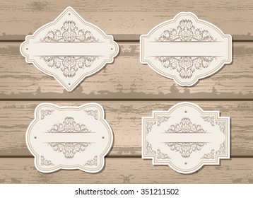 Vector set of labels with frames and decorative elements. On wooden background.