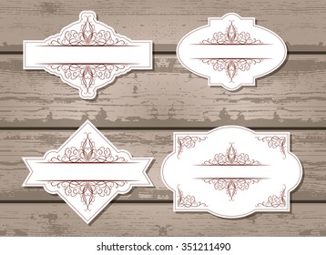 Vector set of labels with ornamental decorative elements. On wooden background.