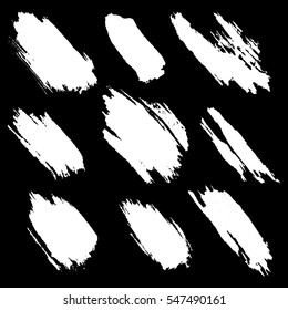 Vector set of white inc splash, blots, smudge and brush strokes, isolated on the black background. Grunge elements for design..