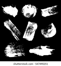 Vector set of white inc splash, blots, smudge and brush strokes, isolated on the black background. Grunge elements for design..