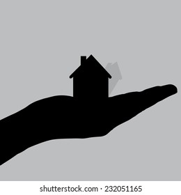 Vector silhouette of a hand with house on a white background.