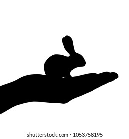 Vector silhouette of hand with rabbit on white background.