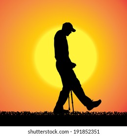 Vector silhouette of a man who walks on crutches at sunset.
