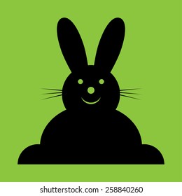 vector sitting smiling black Easter bunny on a green background