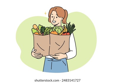 Vegan woman proudly carries paper bags with natural vegetables and fruits bought at farmers fair. Vegan girl buys only organic plant products grown without use of pesticides and nitrates