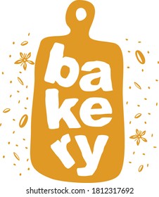 vertikal geschriebene Wortbäckerei in gezogenen Buchstaben auf goldfarbenem Schneidbrett mit Krümel und Körnern um sich herum