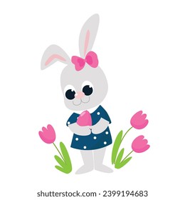 A very cute girl rabbit stands near flowers and holds a colored egg in her hands. Cartoon style characters isolated on white background for Happy Easter greeting cards. The Easter Bunny is very happy.