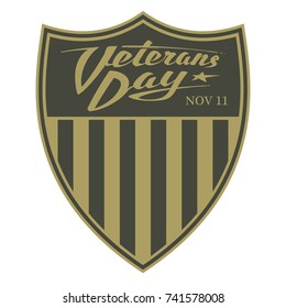 Veterans day. Calligraphic logo on the khaki green shield with a stripes of US flag. Emblem for holiday, that honors military veterans. Handwritten sign in the style of army shoulder sleeve insignia.