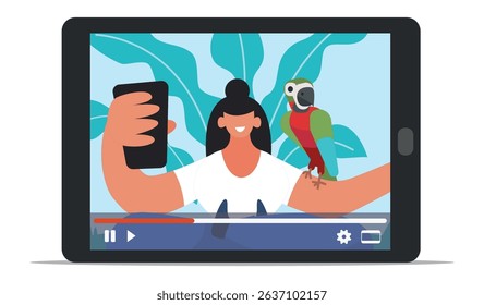 Video blogger recording a lively vlog with her smartphone while an exotic parrot perches on her arm, as the video plays on a tablet in front of her