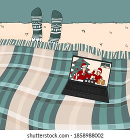 Video call with family or friends on Christmas New Year time. Woman is under the green blue plaid in knitted socks
