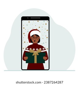 Video congratulations Merry Christmas or New Year. Mobile phone with a woman in a red cap with a gift box. The concept of a safe celebration, online congratulations.
