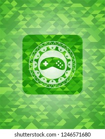 video game icon inside green emblem with triangle mosaic background