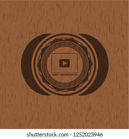 video player icon inside badge with wood background