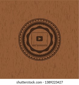 video player icon inside badge with wood background