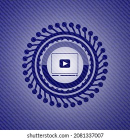 icono del reproductor de vídeo dentro del emblema con fondo jean. 