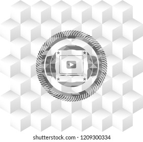 video player icon inside grey badge with geometric cube white background