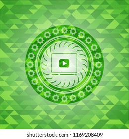 video player icon inside realistic green emblem. Mosaic background