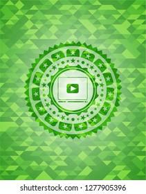 video player icon inside realistic green emblem. Mosaic background