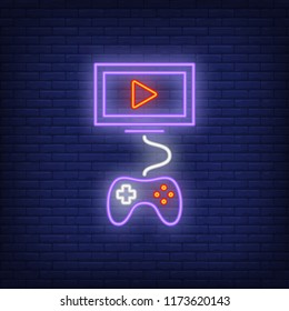 Videogame neon icon. Monitor with play button connected with joystick on brick wall background. Gaming industry concept. Vector illustration can be used for neon signs, billboards, online game.