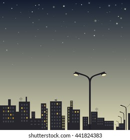 view of the city at night with street lamp in the foreground and stars in the sky