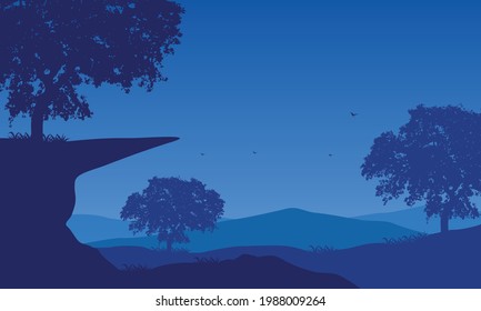A view of the mountains with the aesthetically pleasing silhouette of large trees from the edge of the city at night. Vector illustration of a city