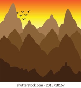 View of the mountains at sunset with a flock of birds in the distance.