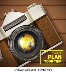 Vintage camera and text block on wooden table. World map reflection on lense.