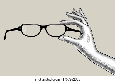 Vintage engraved drawing of female hands holding eye glasses. Vector illustration